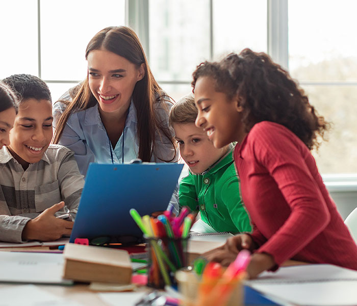 Teacher helping students at a classroom table